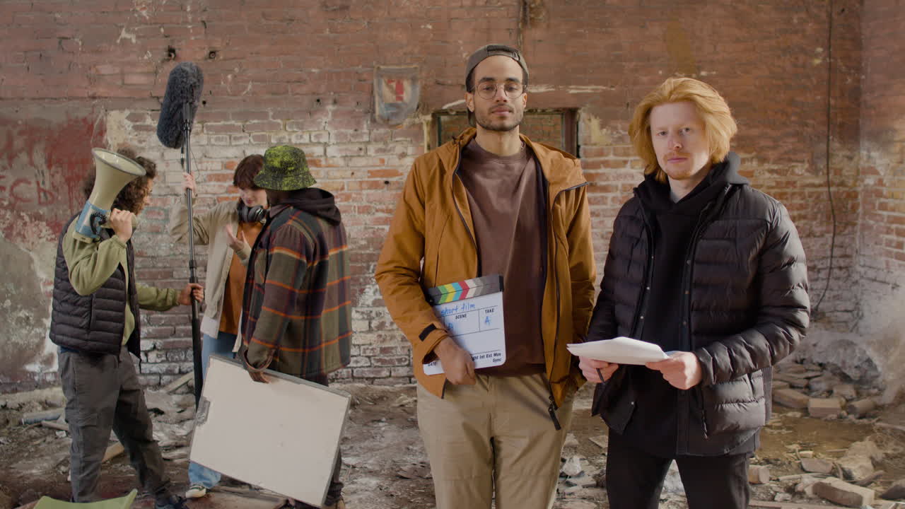 dos compañeros de producción mirando la cámara en un edificio en ruinas