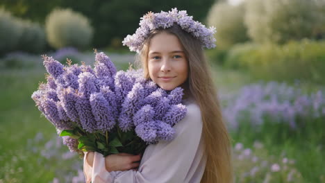 young girl holding a large lilac bouquet in a garden