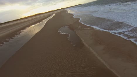 Drone-flying-fast-and-low-at-the-beach-towards-the-sunset-in-the-Netherlands