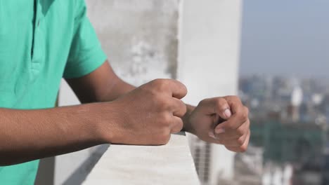 man with clenched fists on a balcony overlooking a city