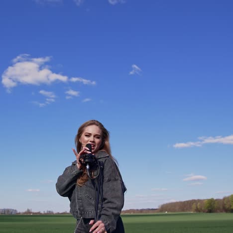 girl singing with microphone on nature. young woman singing with microphone on nature