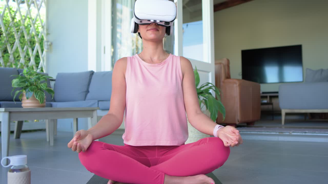 VR headset is starting yoga on patio, woman is following gestures, sitting in meditation for calm