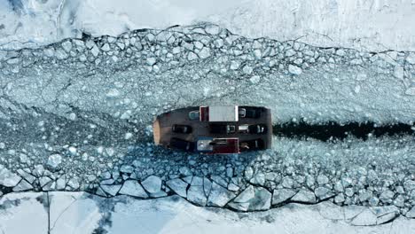 transbordador de automóviles que transporta vehículos a través del camino de la capa de hielo del lago congelado roto, antena arriba hacia abajo
