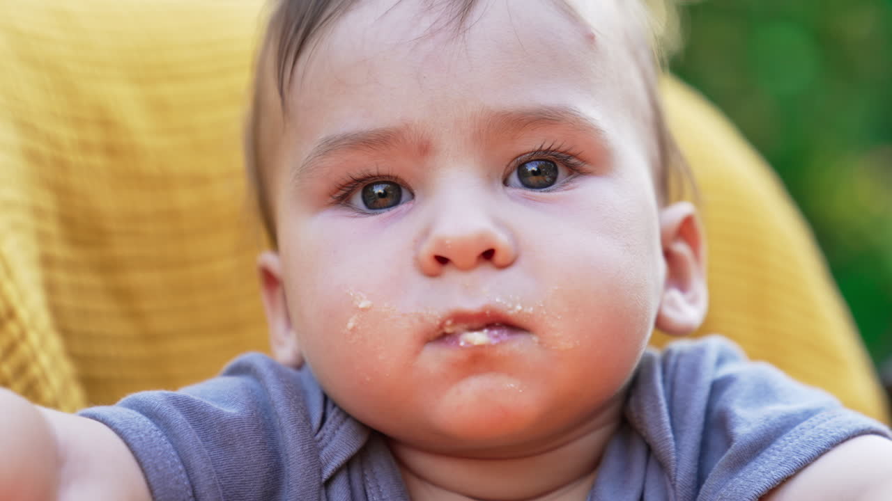 Face of a cute toddler with grimy mouth and cheeks. Close up. Baby nutrition concept. Blurred background.