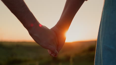 a young couple holds hands against the backdrop of a picturesque valley where the sun sets