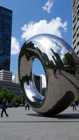 reflective urban sculpture with sky and city reflections