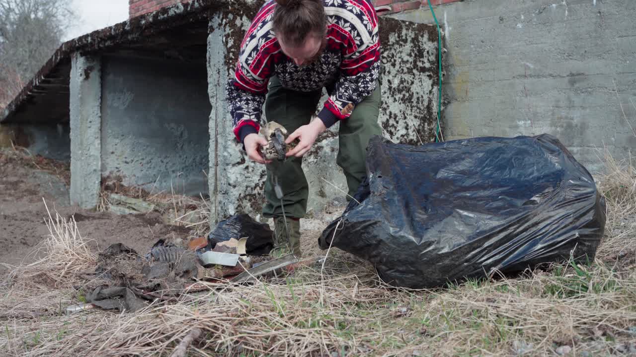 hombre poniendo basura y cosas viejas en la bolsa de basura negra