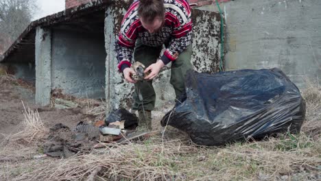 Hombre-Poniendo-Basura-Y-Cosas-Viejas-En-La-Bolsa-De-Basura-Negra