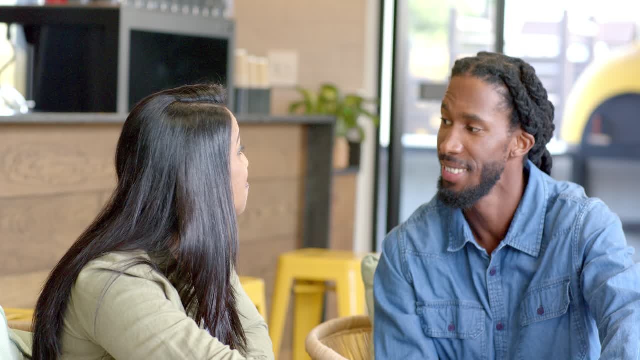 Camera focusing on laptop sparking diverse coworkers pointing at screen discussing project at cafe