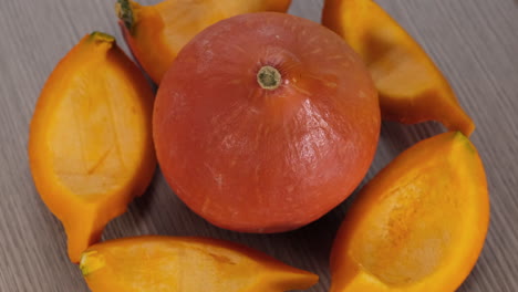 orange pumpkin and slices rotating on wooden background