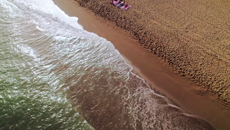 Birdseye-view-of-Cabopino-beach-in-Calahonda,-Spain,-tilting-up-and-moving-backwards-over-the-sea