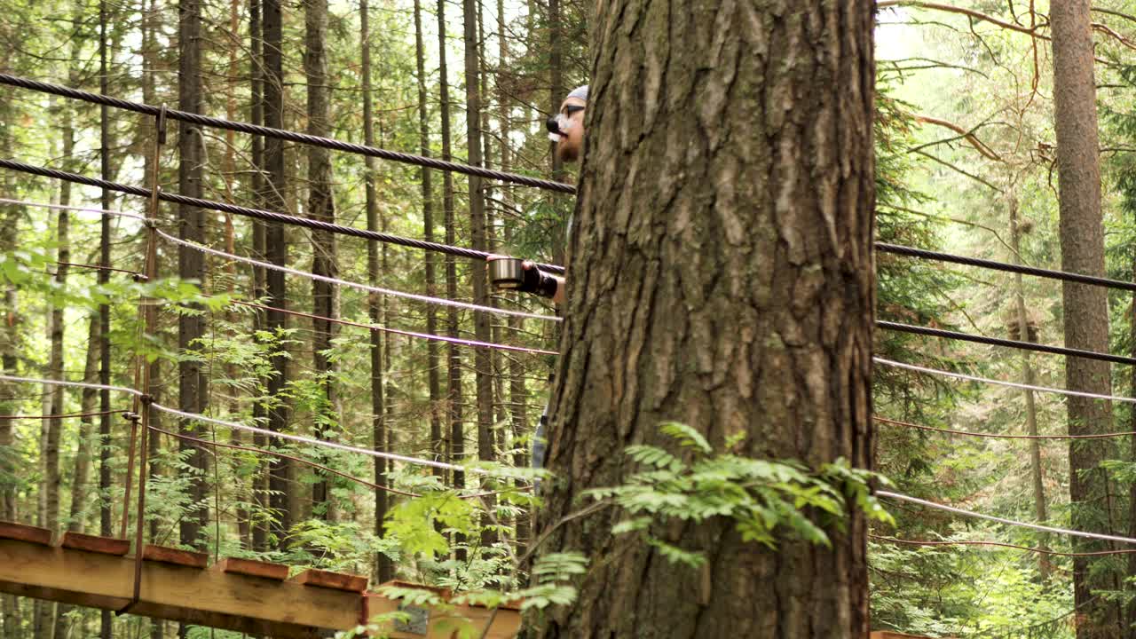 человек, идущий по подвесному мосту в лесу.