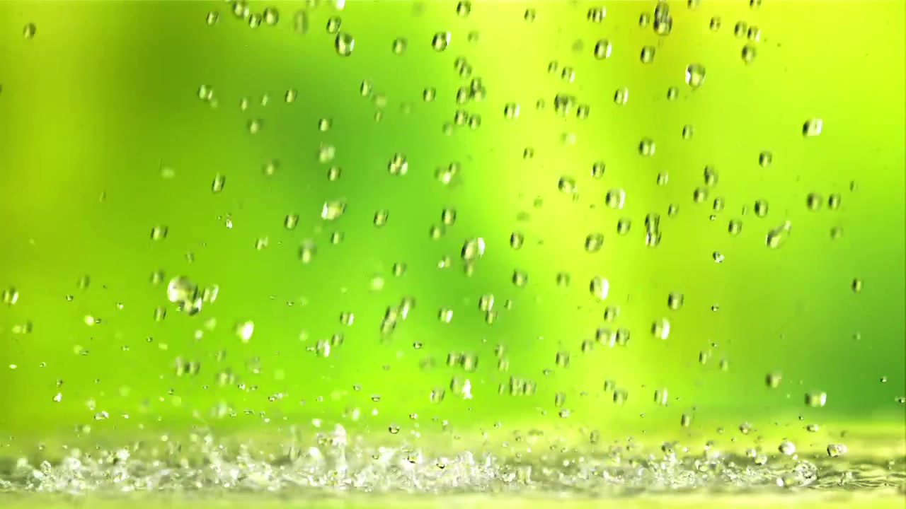 Gocce di pioggia fresca che cadono e schizzano su sfondo verde