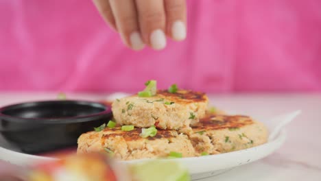 Adding-garnish-to-a-plate-of-delicious-crab-cakes