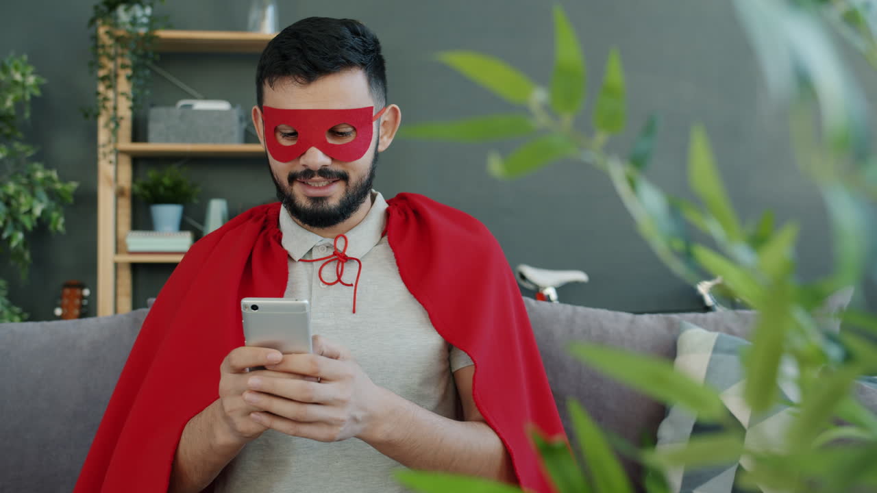 Man in Superhero Costume Using Smartphone at Home