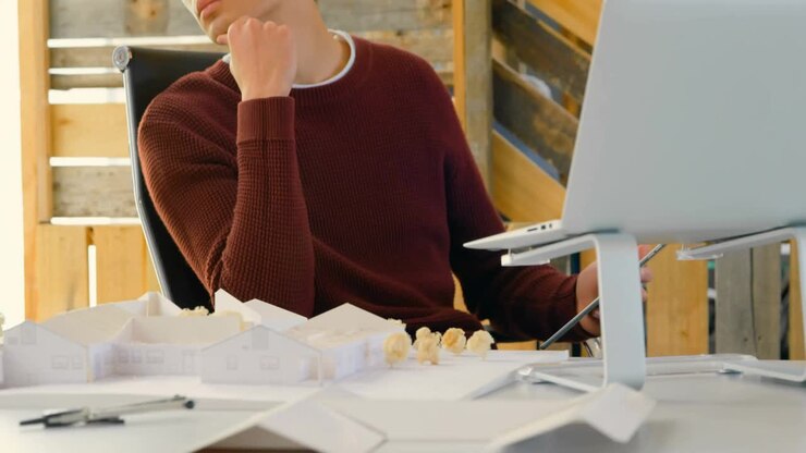 Designer gazing at drafting desk in loft as social media icons clustering showing engagement growth