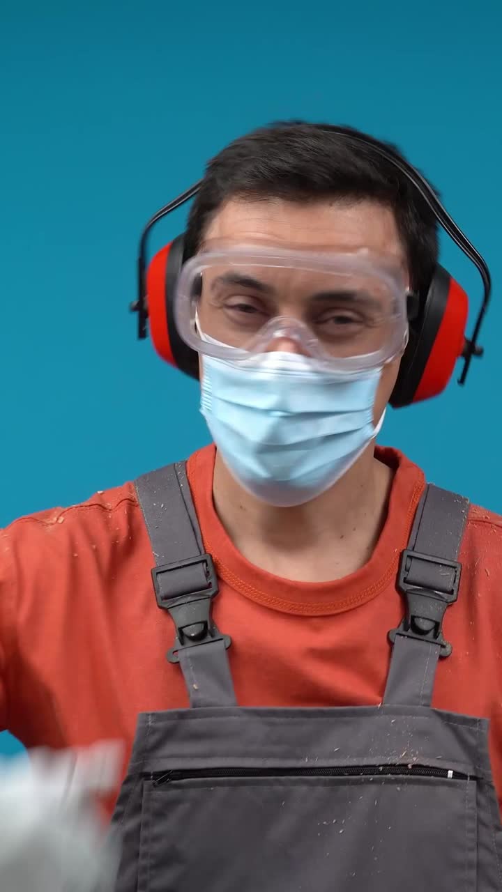 Worker in full PPE (mask, glasses, ear protection, gloves) giving a thumbs up