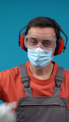 worker in full ppe (mask, glasses, ear protection, gloves) giving a thumbs up
