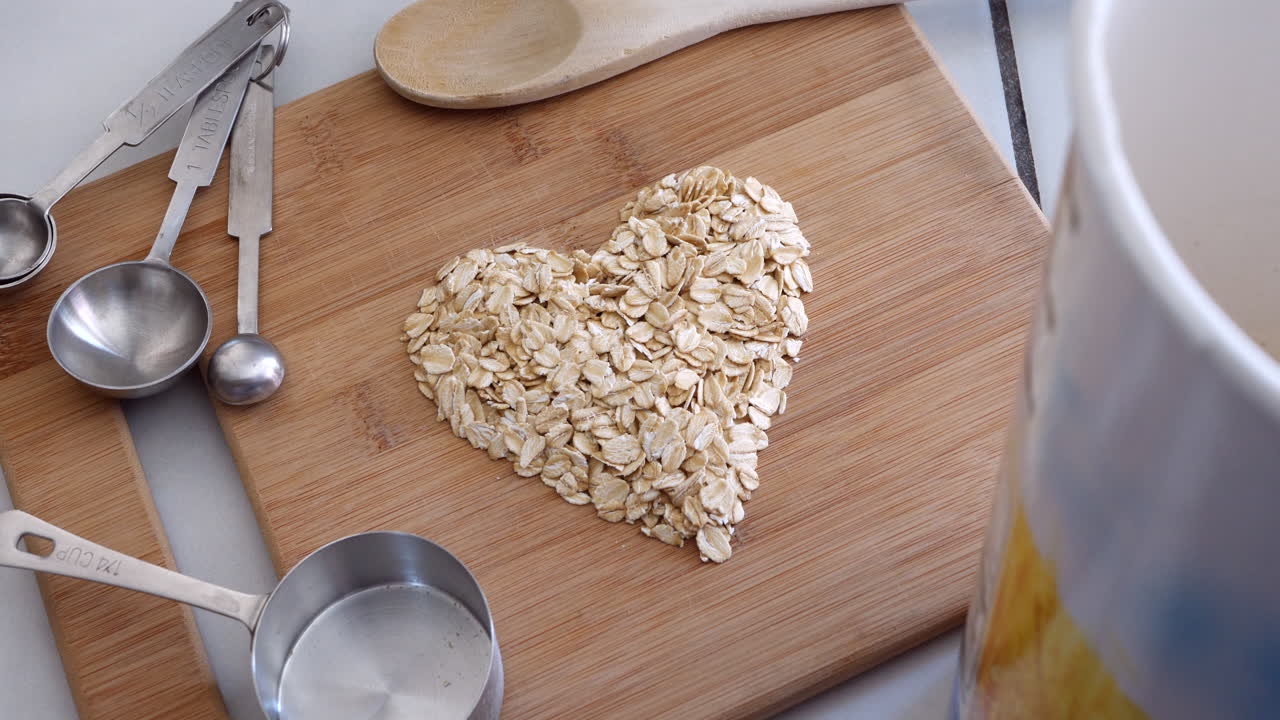 un montón de cereales de avena en forma de corazón con utensilios de cocina para un desayuno saludable de avena de arriba hacia abajo