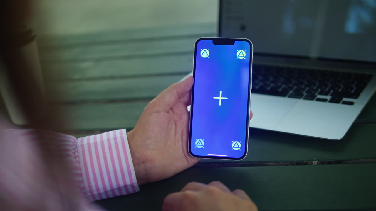 Woman hand holding phone with chroma key screen outdoor. Smartphone with green screen close-up