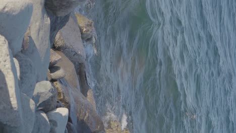 sea water waves crashing against white rocks in slow motion at the ocean shore