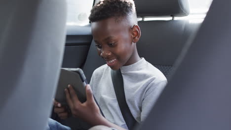 african american boy enjoys a tablet in the backseat of a car