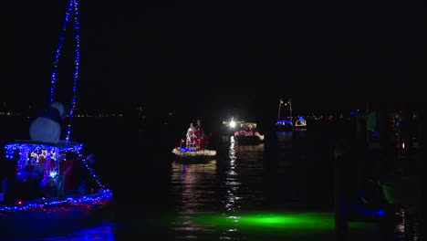 a holiday parade of boats makes its way through a harbor in florida