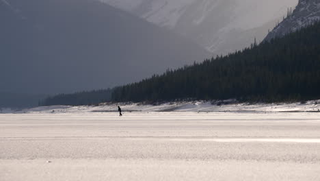 hockey skater on a frozen lake in kananaskis country. spray lakes.