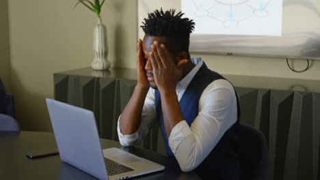 Side-view-of-young-black-businessman-working-on-laptop-in-conference-room-of-modern-office-4k