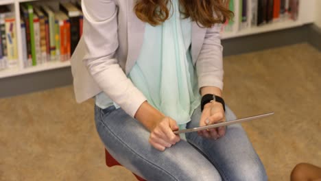 maestro enseñando a un niño en una tableta digital en la biblioteca