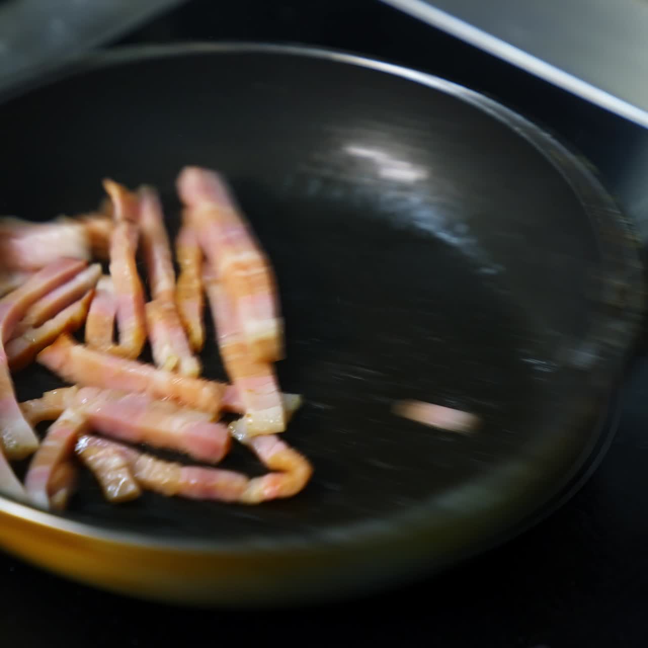 Chef cooking breakfast. Turning an amazing crispy bacon, rich in fat and colour. Sizzling and smoking in a hot pan