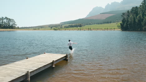 business woman jumping off jetty in lake splashing in water enjoying freedom