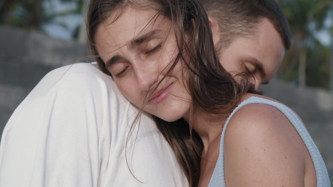 una joven pareja caucásica abrazándose al aire libre.