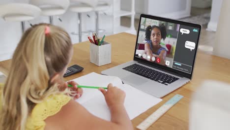 Schoolgirl-using-laptop-for-online-lesson-at-home,-with-her-colleague-and-web-chat-on-screen