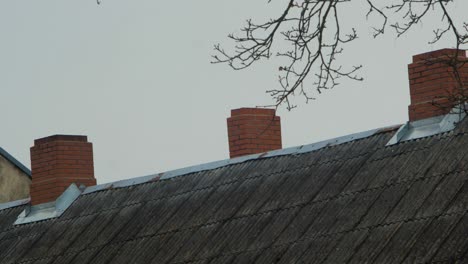 Red-chimney-of-the-residential-building-against-the-overcast-sky,-gray-autumn-day,-cityscape-rooftop,-distant-medium-shot