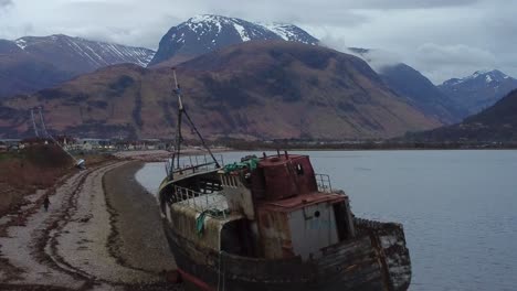 Ein-Luftdrohnenvideo-Des-Alten-Bootes-Von-Corpach-In-Fort-William-Mit-Dem-Höchsten-Gipfel-Großbritanniens,-Nevis,-Im-Hintergrund