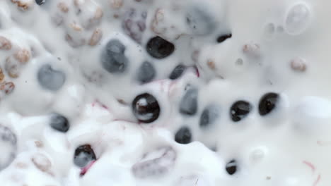 proceso de mezcla de bayas de granola vista superior. muesli de cereales con leche de calcio flotante