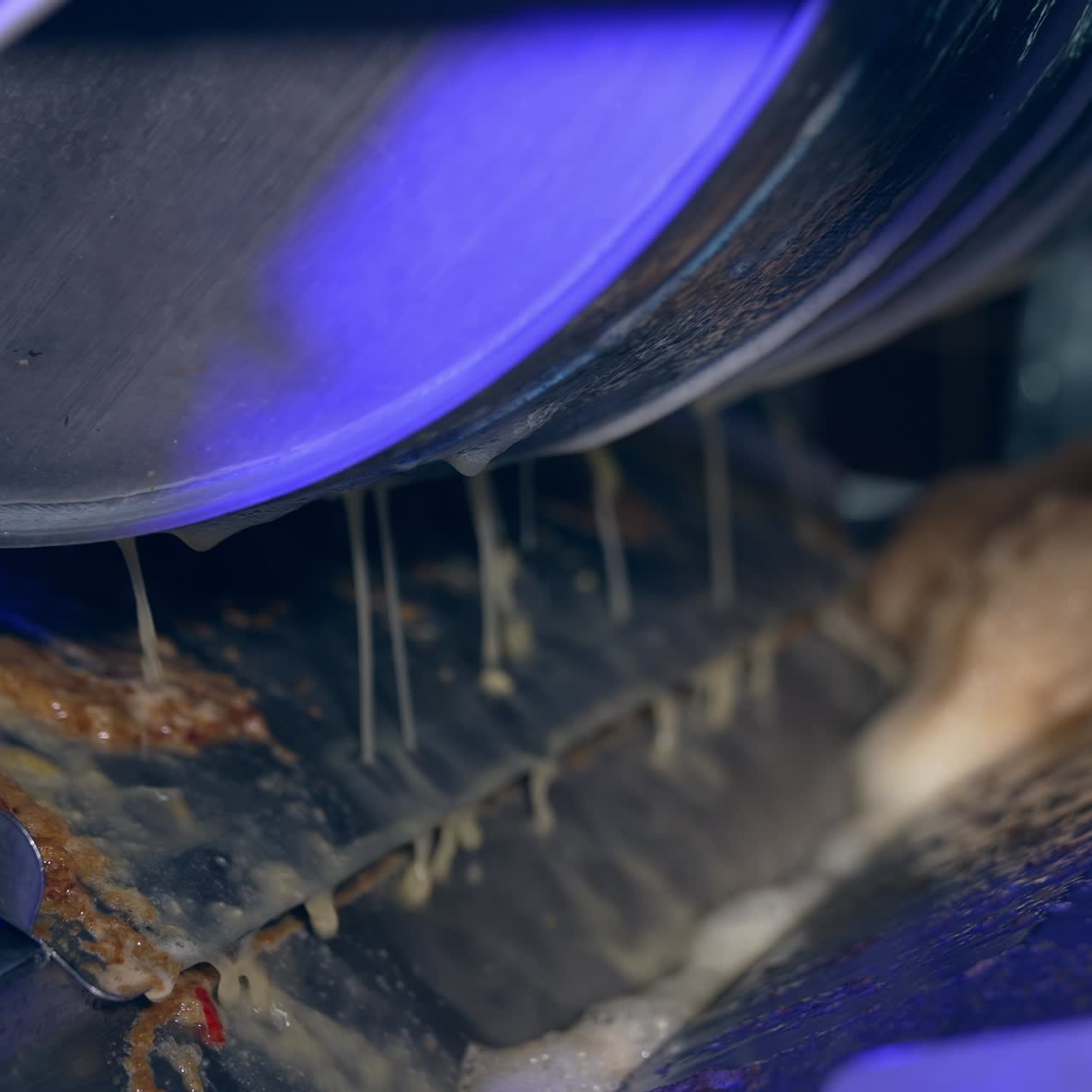Wide shaft rotating in the machine and producing juice. Freshly-squeezed juice pouring from the roller. Work of equipment at modern food factory