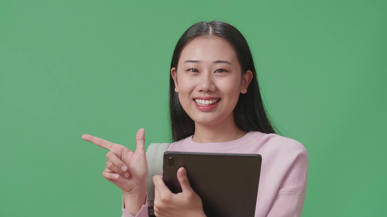 태블릿과 직접 손가락을 사용하는 아시아 여성 학생이 녹색 스크린 스튜디오에서 을