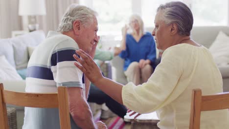 senior biracial woman comforting sad diverse senior male friend at support group, slow motion