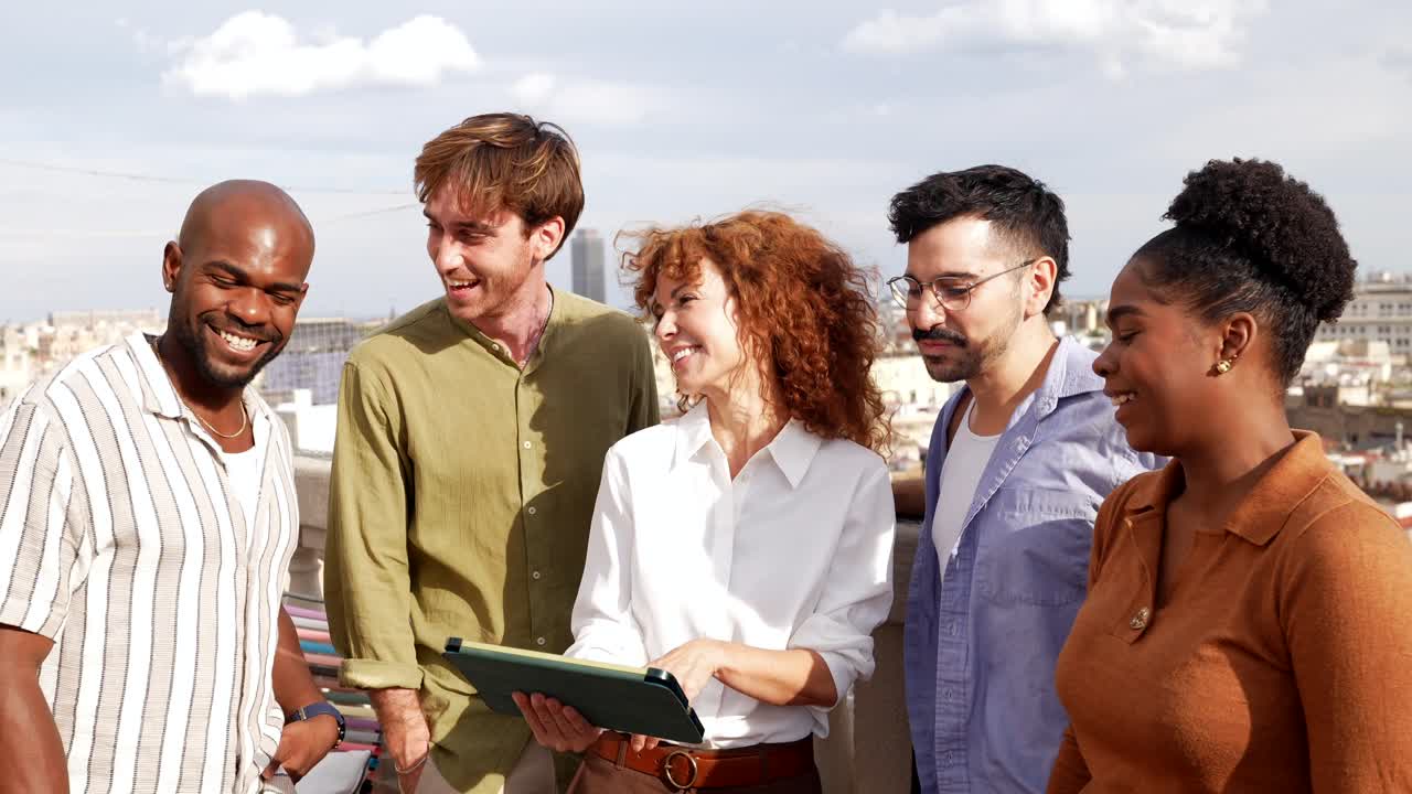 Gruppo eterogeneo di colleghi che ridono e parlano su un tetto in città
