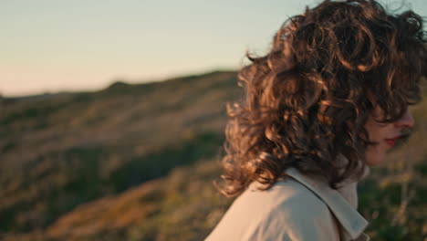 closeup girl body going green hill in beige coat. serene woman hiking evening