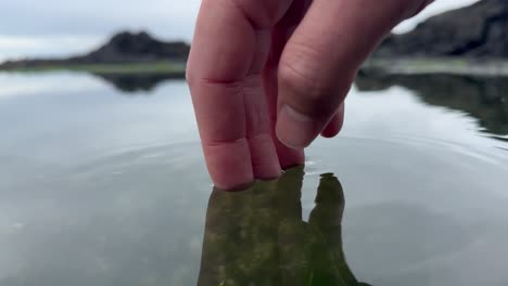 Closeup-as-a-caucasian-dip-their-hands-into-cool-water-in-nature