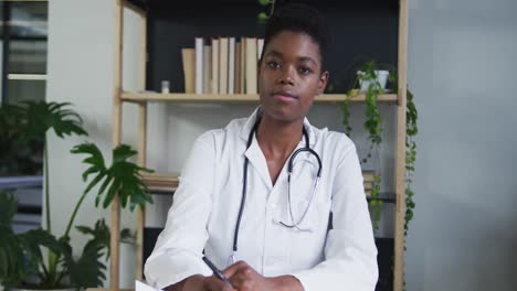 portrait of african american female doctor having a video chat listening and writing notes