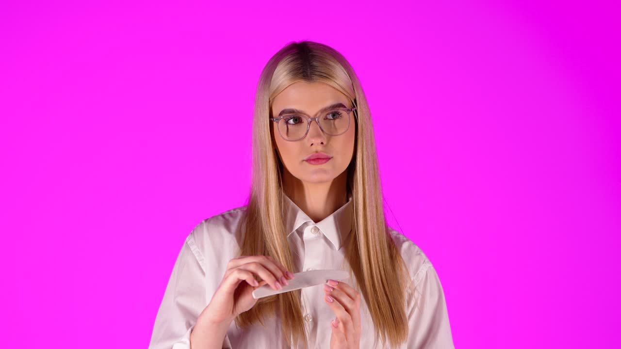 primer plano joven adolescente descarado haciendo manicura, fondo rosa aislado, estudio