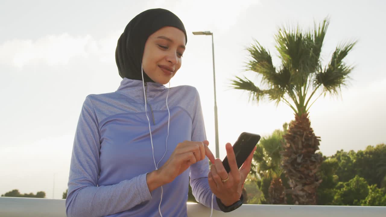 Woman wearing hijab listening music outside