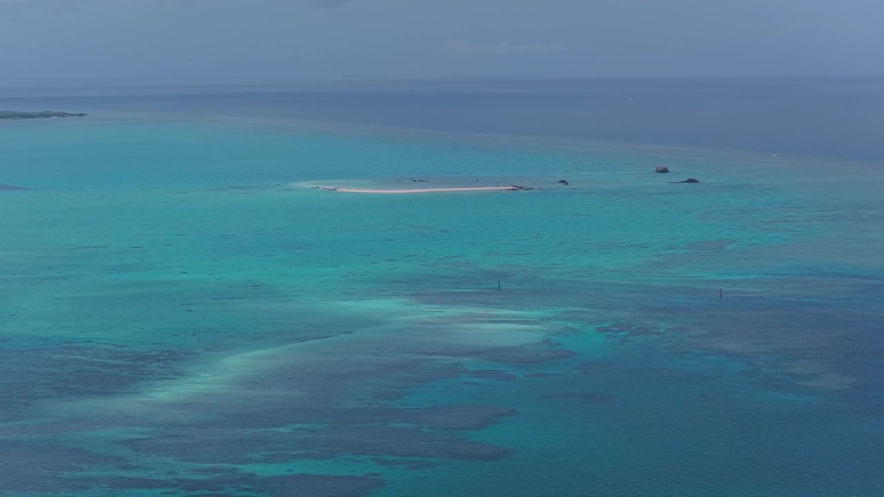 Metraje aéreo horizontal con paneo a la derecha mientras se desplaza a la izquierda sobre las aguas turquesas y el banco de arena que rodean la Isla Fantasma y la Isla Hama, Islas Yaeyama, Okinawa, Japón