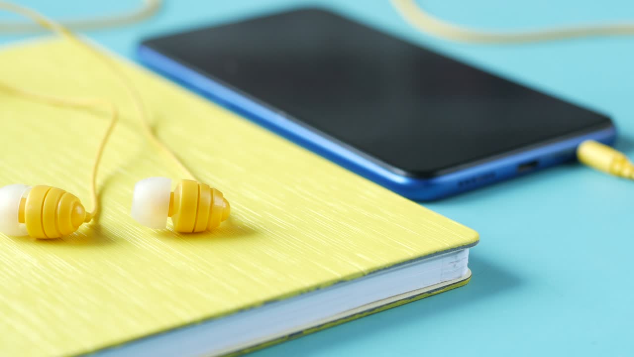 teléfono inteligente y auriculares sobre fondo de madera.