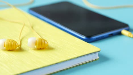 teléfono inteligente y auriculares sobre fondo de madera.