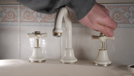 handyman removes the top of a bathroom tap